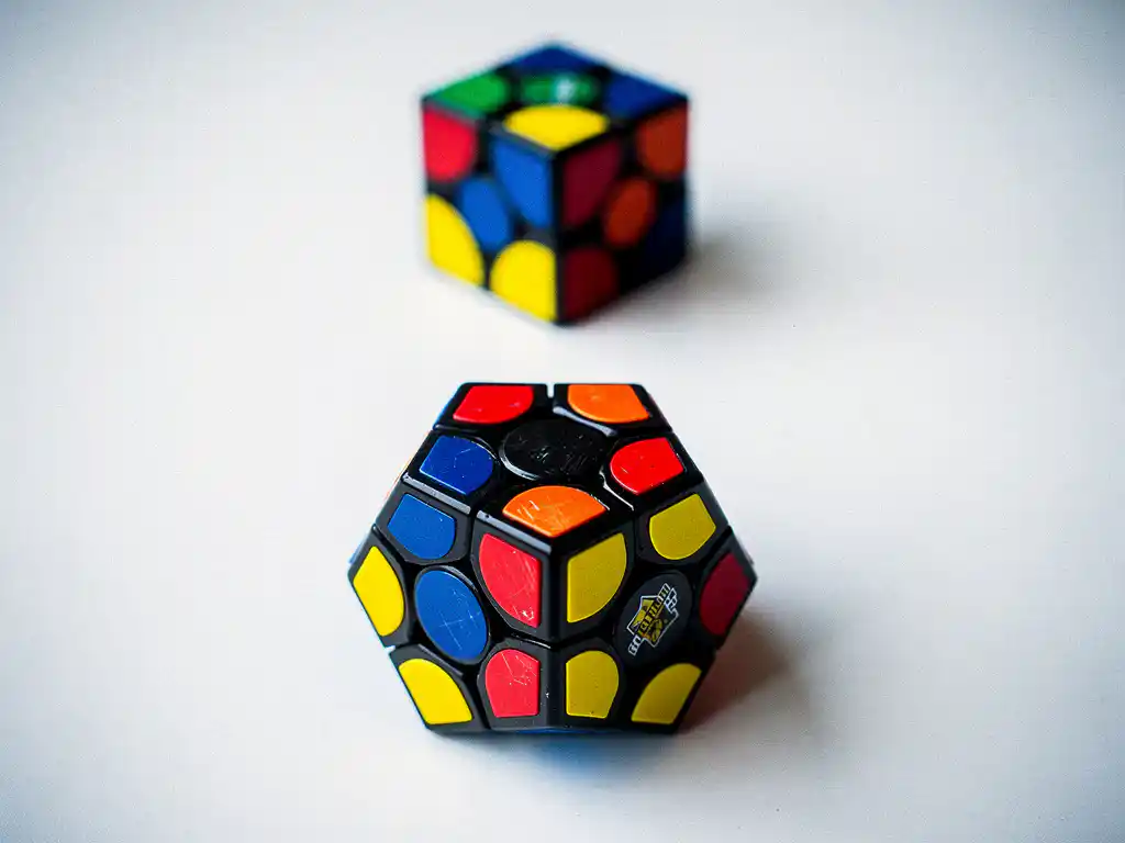 Wedstrijdklare megaminx puzzel met twaalf kleurrijke pentagonale vlakken op wit oppervlak, tweede megaminx onscherp op de achtergrond.