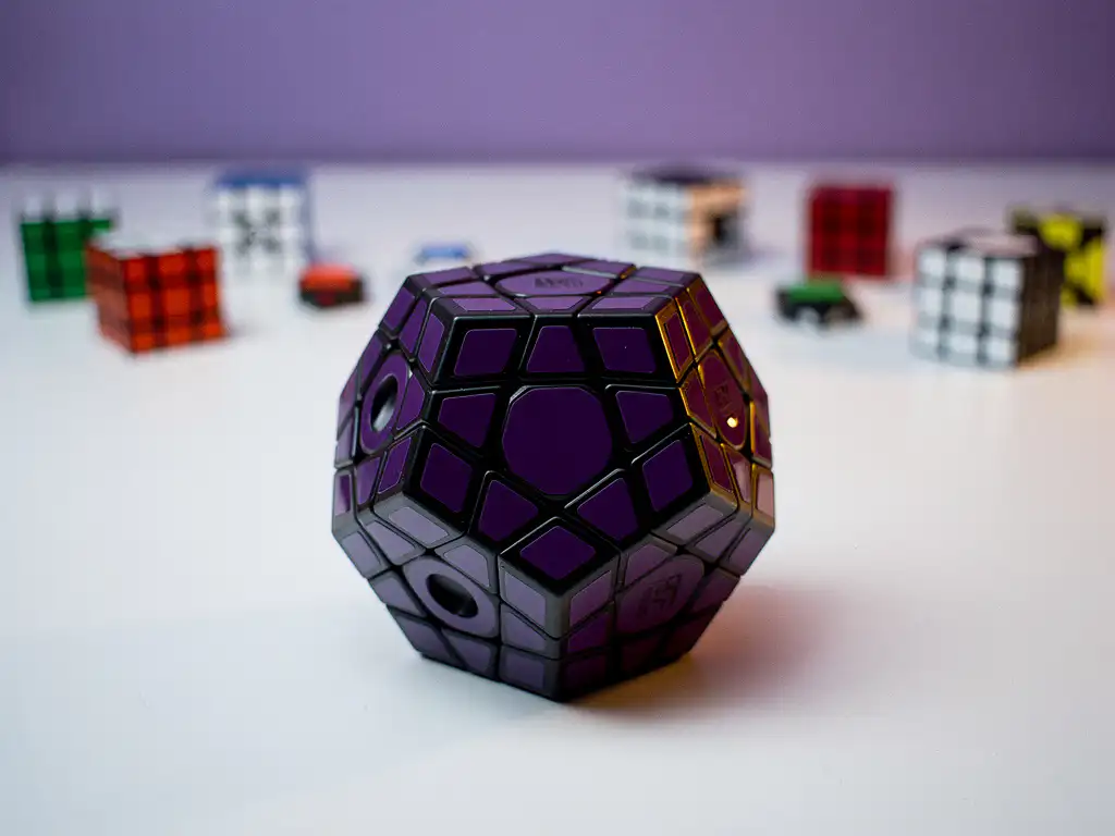 Paarse en zwarte megaminx dodecaëder puzzel op wit bureau, met wazige puzzelstukjes op de achtergrond.