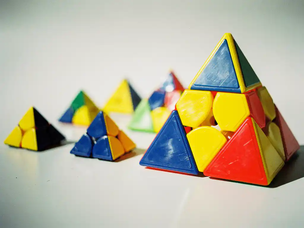 Collectie pyraminx puzzels in verschillende groottes en kleurenschema's op wit oppervlak, van beginner tot competitieniveau.